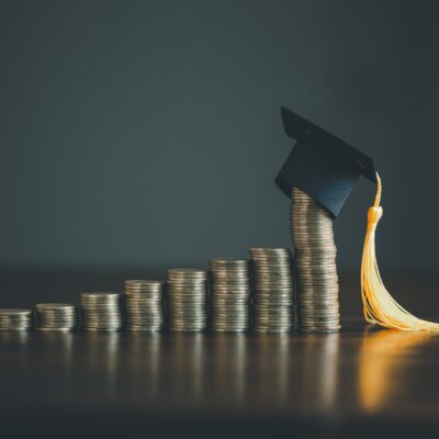 financial education image of a graduation cap on bar graph of coins